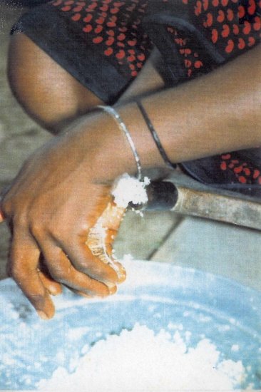 VILLAGER USING THE TRADITIONAL COCONUT GRATER IN TANZANIA